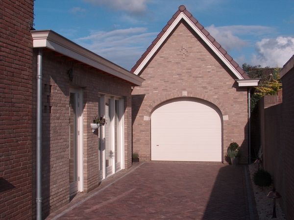 Garage met getoogde deur en aanbouw.