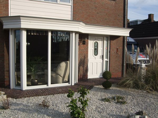 Erker aan een bakstenen woning in Hoeven, bus van Bouwbedrijf van Zundert in de oprit.